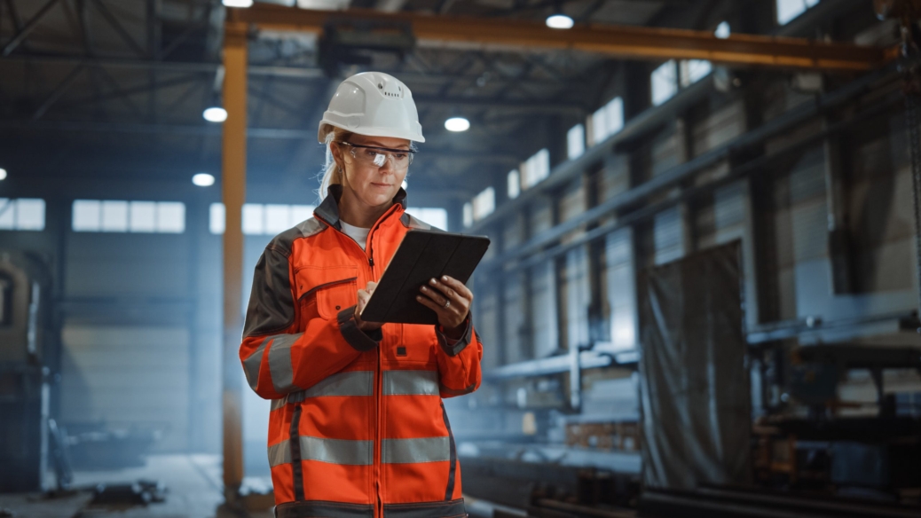 Woman in safety gear, looking at clipboard